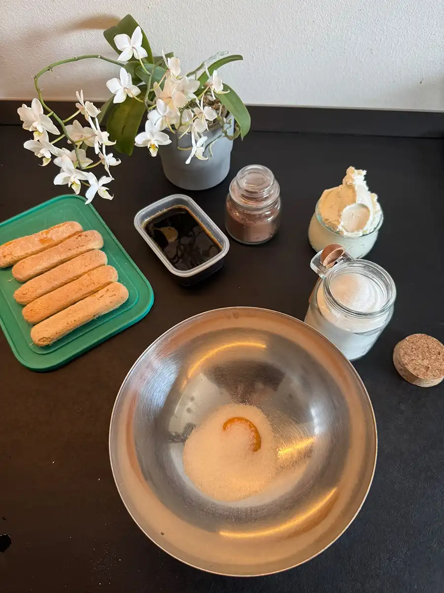 Uovo e zucchero in una ciotola insieme agli ingredienti della ricetta.